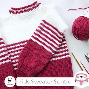 May include: A white and pink striped sweater knit with a loom. The sweater has a high neck and long sleeves. The sweater is laid flat on a white surface with pink yarn and knitting needles.