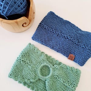 May include: Two knitted headbands, one blue and one green, are displayed. The blue headband has a small brown tag that says "Made With". A wooden yarn bowl with blue yarn is in the background. The green headband has a circular design in the center.