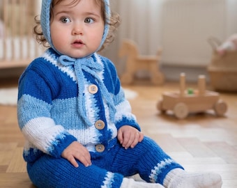 Könnte beinhalten: Ein gestricktes Baby-Set bestehend aus einer hellblauen Mütze mit Bindeband, einer langärmeligen Strickjacke mit horizontalen Streifen in Blau- und Weißtönen mit drei Holzknöpfen, einer passenden blauen Hose und schlichten weißen Socken.