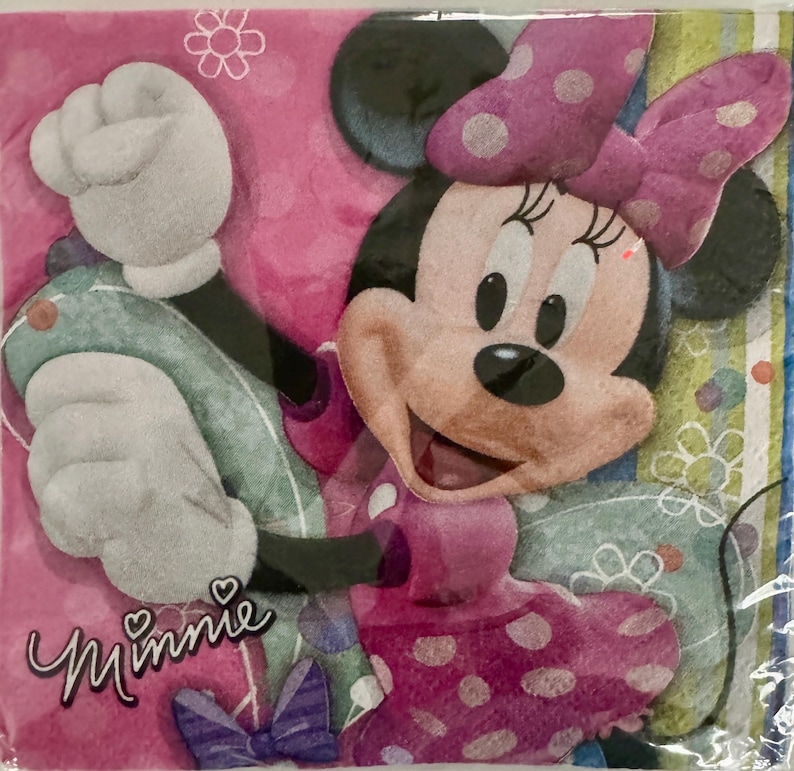 May include: Pink and white Minnie Mouse napkin with a polka dot pattern and the word "Minnie" printed on the bottom left corner.