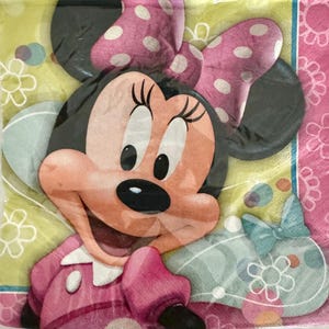 May include: A pink and yellow party napkin with a cartoon image of Minnie Mouse. Minnie Mouse is wearing a pink dress with white polka dots and a pink bow with white polka dots.