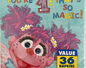 May include: A blue and pink Sesame Street themed party napkin with a picture of Abby Cadabby. The napkin has the text "You're 1! That's so magic!" and a value pack of 36 napkins.