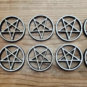 May include: Ten circular wooden coasters with a pentagram design. Each coaster features a black outer ring and a white pentagram within. The coasters are arranged on a wooden surface.