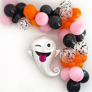 May include: A Halloween-themed balloon garland featuring black, orange, and pink balloons, along with clear balloons filled with bat confetti. A silver ghost-shaped balloon with a winking eye and tongue adds a playful touch to the festive decor.