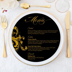 May include: A black and gold wedding menu with a decorative flourish design. The menu lists the salad, entree, and dessert options for the wedding reception. The text reads: "Salad: Mixture of Iceberg and Romain Lettuce with Grape Tomatoes, Cucumbers, and Shredded Carrots with a Choice of Ranch Dressing and Balsamic Vinaigrette. Entrée: Chicken Marsala Grilled Chicken Thighs Topped with a House-Made Mushroom Marsala Wine Sauce, Served with Garlic Mashed Potatoes and Oven Roasted Vegetables. Sweet Chili Garlic Salmon Broiled Filet of Salmon topped with a Sweet Chili Garlic Glazed, Served with Garlic Mashed Potatoes and Oven Roasted Vegetables. Dessert: Wedding Cake White Chocolate with Raspberry, Chocolate Oreo."
