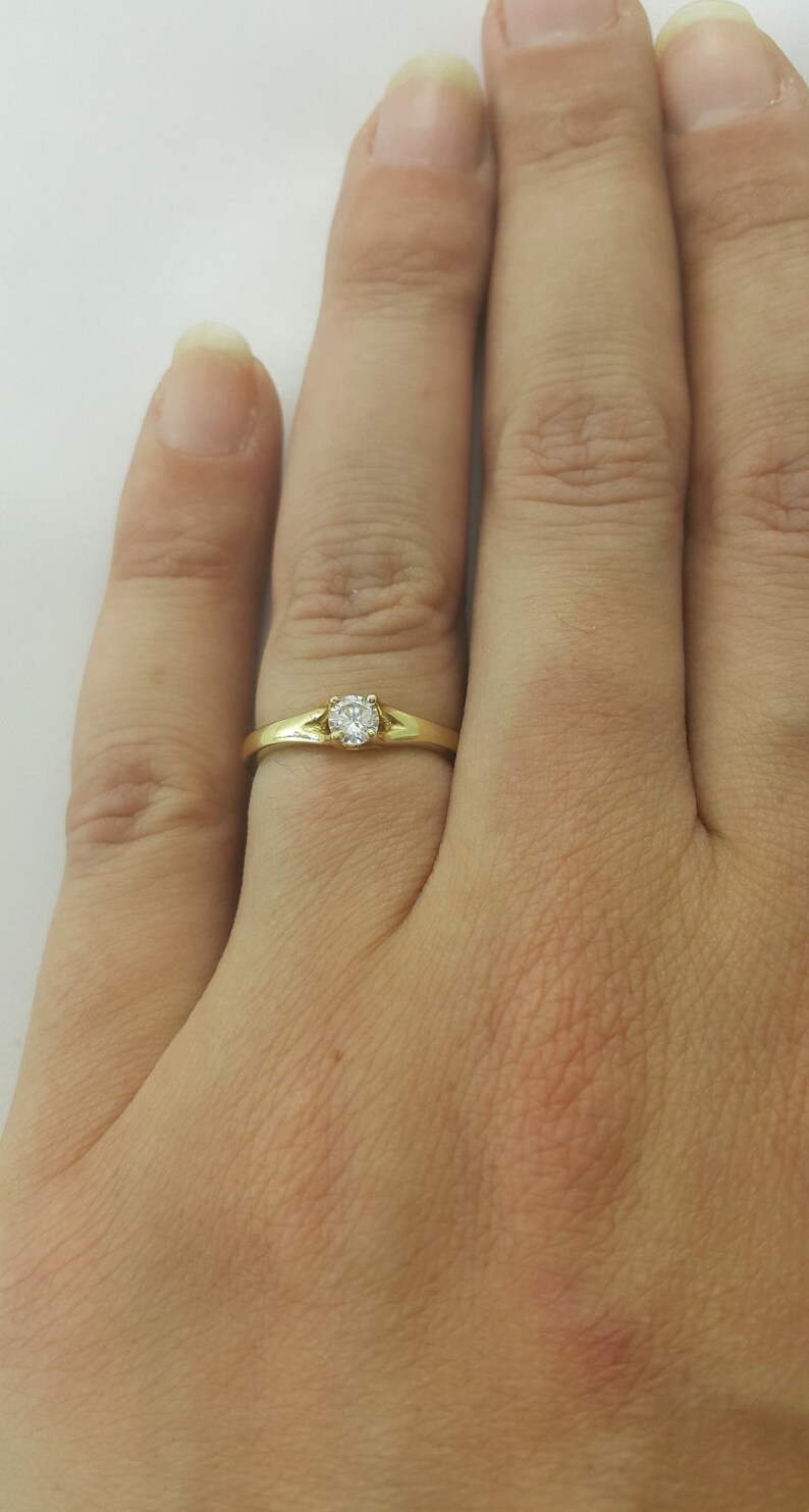 May include: A simple gold band ring with a single, small, round diamond.