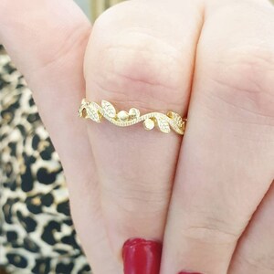May include: A delicate gold ring with a vine design featuring small leaves and beads.
