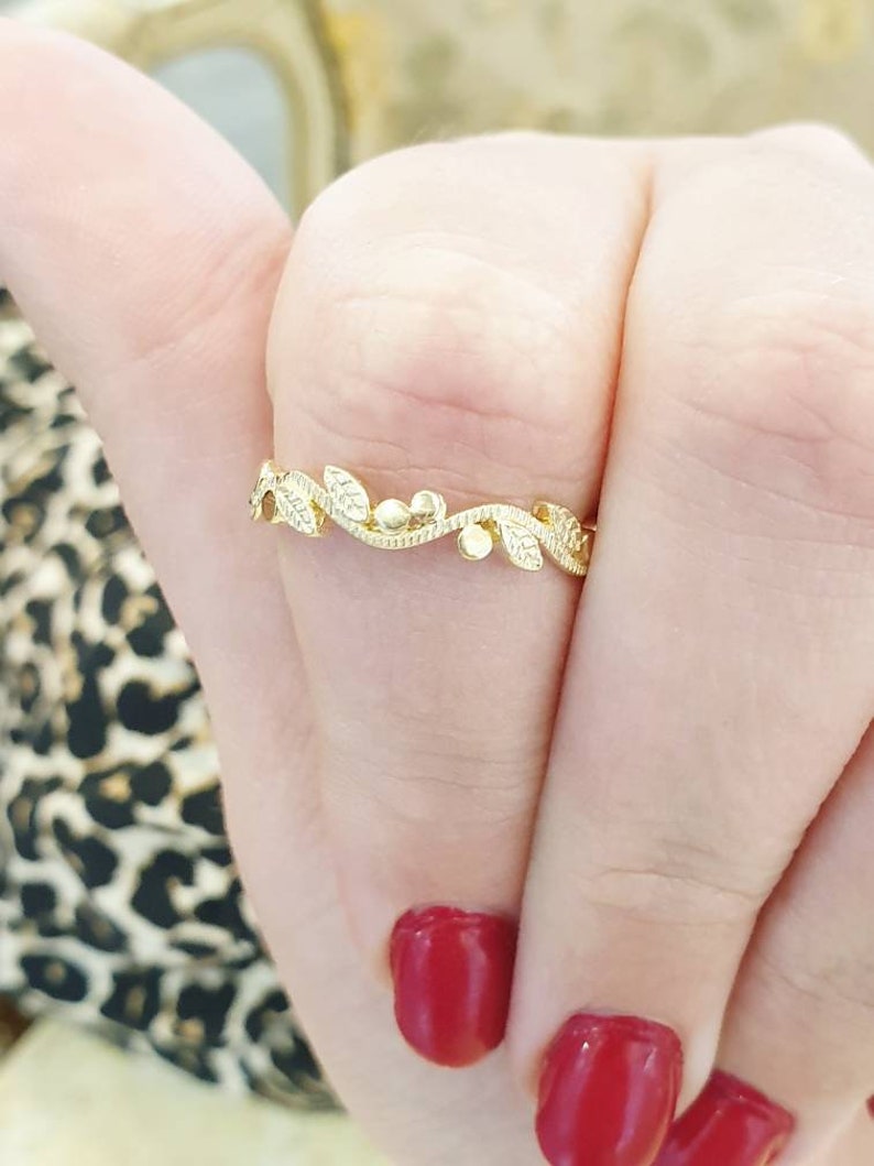 May include: A delicate gold ring with a vine design featuring small leaves and beads.