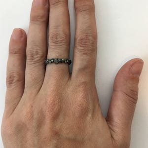 May include: A silver ring with a delicate leaf design and small clear stones.