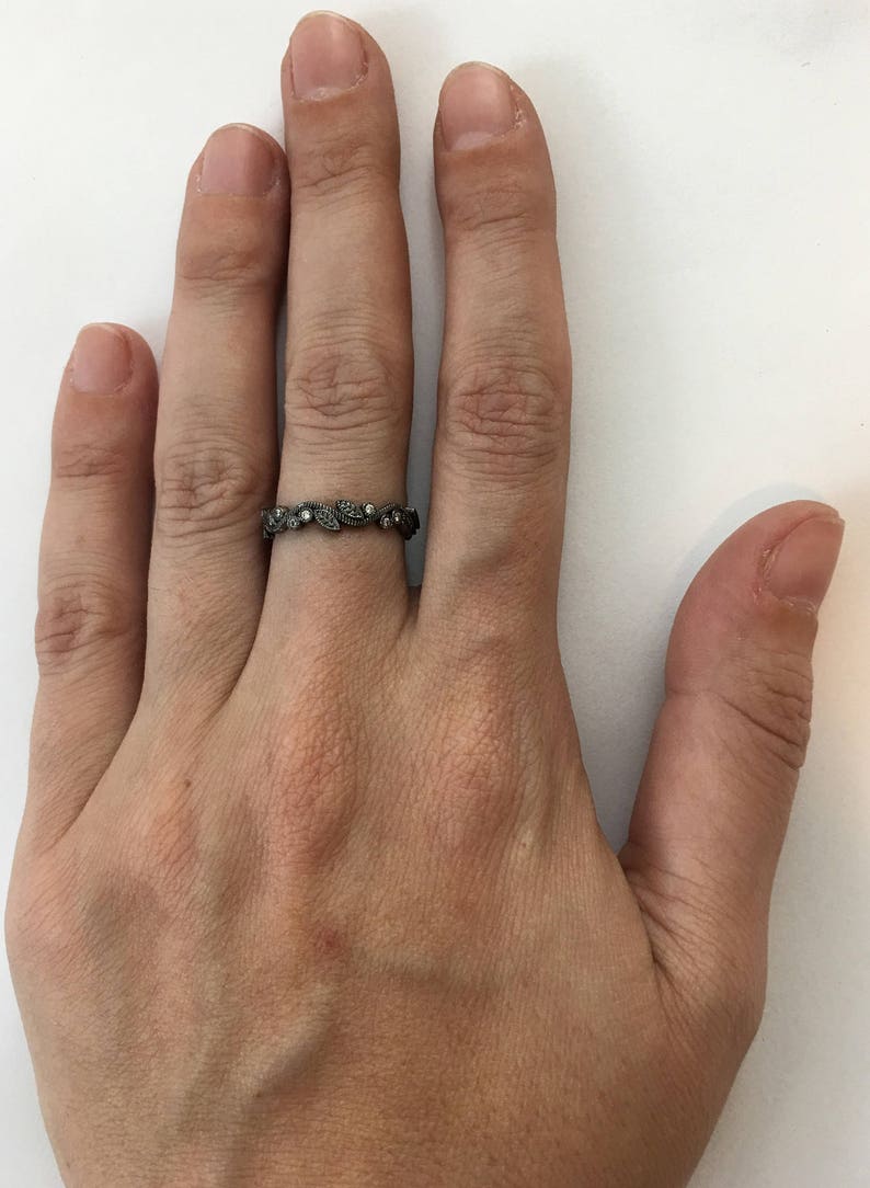 May include: A silver ring with a delicate leaf design and small clear stones.