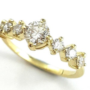 May include: A gold band ring with a central round diamond and smaller diamonds set along the band.
