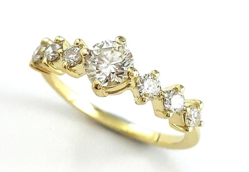 May include: A gold band ring with a central round diamond and smaller diamonds set along the band.