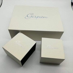 May include: Three white boxes with the word "Gispan" printed on them. The boxes are nested inside each other, with the largest box on the bottom and the smallest box on top.
