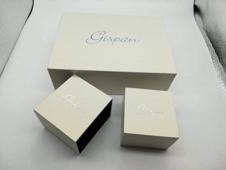 May include: Three white boxes with the word "Gispan" printed on them. The boxes are nested inside each other, with the largest box on the bottom and the smallest box on top.