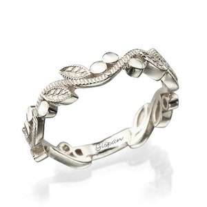 May include: A delicate silver band ring with a leafy design. The ring is engraved with the word "Gispan" on the inside.