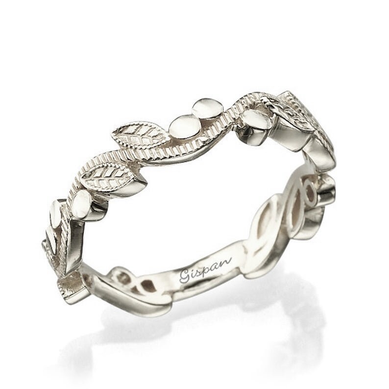 May include: A delicate silver band ring with a leafy design. The ring is engraved with the word "Gispan" on the inside.