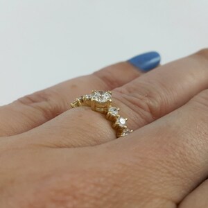 May include: A gold ring with a row of small diamonds set in a curved design.