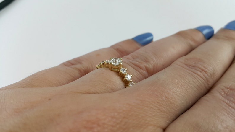 May include: A gold ring with a row of small diamonds set in a curved design.