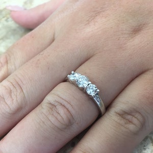 May include: A silver ring with three round diamonds set in a row.
