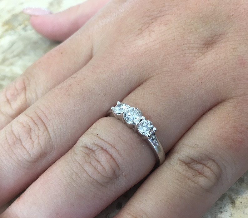 May include: A silver ring with three round diamonds set in a row.