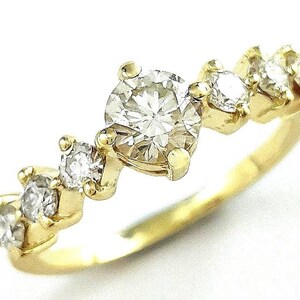 May include: A gold band ring with a row of five clear diamonds. The largest diamond is in the center and the other four diamonds are smaller and are on either side of the center diamond.