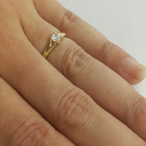 May include: A gold ring with a single clear stone set in the center.