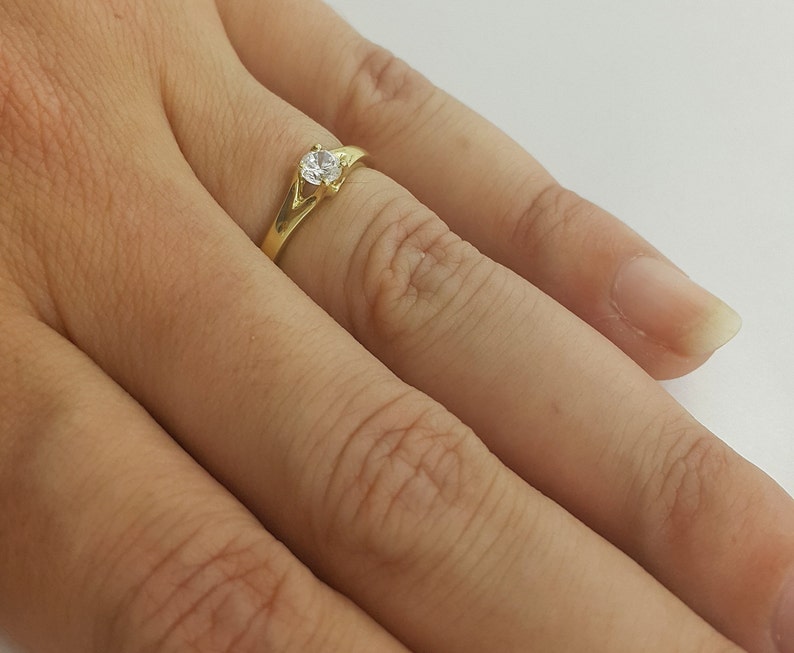 May include: A gold ring with a single clear stone set in the center.