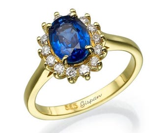 May include: A gold ring with a large oval blue sapphire surrounded by a halo of smaller diamonds. The ring is inscribed with "925 Gisman".