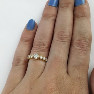 May include: A gold band ring with a row of round diamonds. The center diamond is larger than the others.