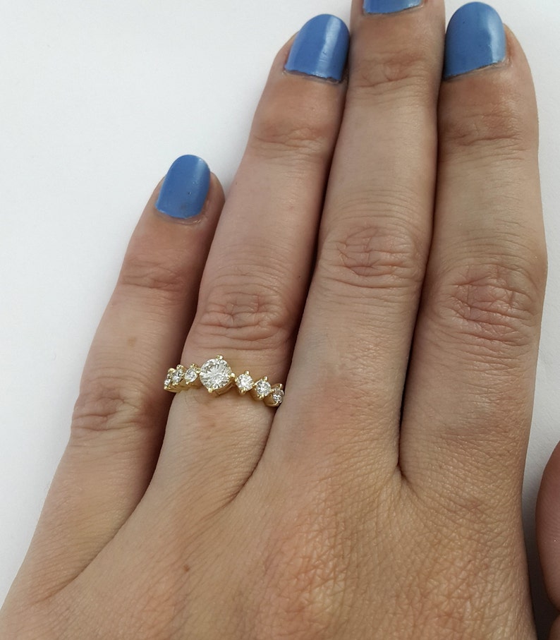 May include: A gold band ring with a row of round diamonds. The center diamond is larger than the others.