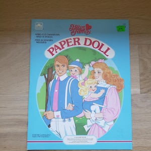 May include: A vintage "Heart Family Paper Doll" book. The cover shows a family illustration within a blue oval frame. The family includes a father, mother, and two children. The book is a Golden Book and includes pre-cut fashions and dolls.