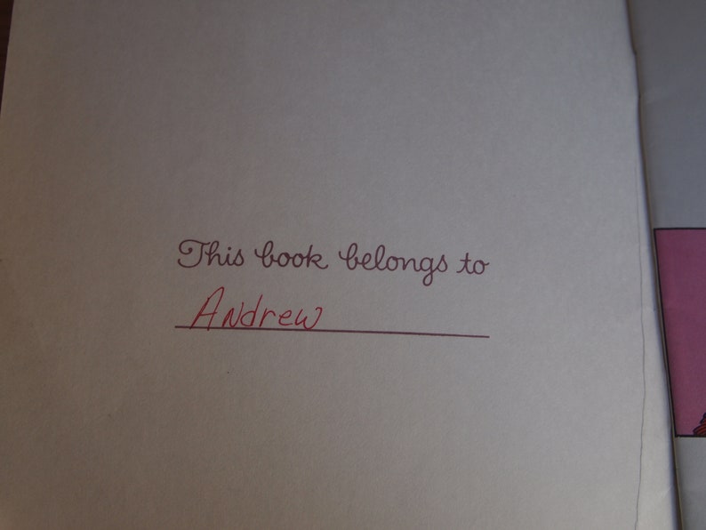 May include: A white book with the inscription "This book belongs to" followed by a line for a name. The name "Andrew" is written in red ink.