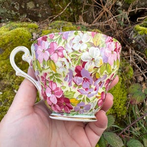 May include: A set of three ceramic mugs with a speckled, matte finish. The mugs are in shades of cream, light gray, and dark gray. Each mug has a simple, minimalist design, perfect for coffee or tea.