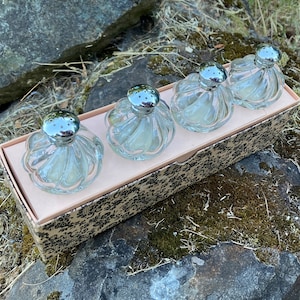May include: Set of four clear glass salt shakers with silver tops in a patterned box. The shakers have a fluted design.