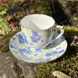 May include: A white ceramic mug with a black handle and the text "But First, Coffee" in a black, handwritten-style font. The mug is on a white surface.
