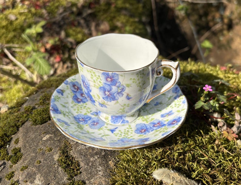 May include: A white ceramic mug with a black handle and the text "But First, Coffee" in a black, handwritten-style font. The mug is on a white surface.