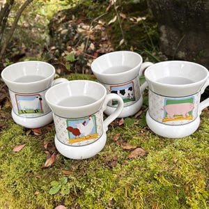 May include: Four white ceramic mugs with farm animal illustrations. Each mug features a different animal: a sheep, a cow, a pig, and a chicken. The mugs have a handle and a decorative border with a patterned design.
