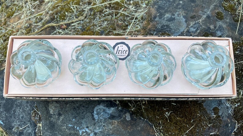 May include: Set of four clear glass cabinet knobs with a fluted design. The knobs are in a box with the text "Irice Product" printed on it.