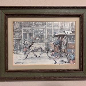May include: A framed illustration of a horse-drawn carriage traveling down a cobblestone street in a city. The carriage is pulled by a white horse and is carrying passengers. The illustration is in a green and brown frame.