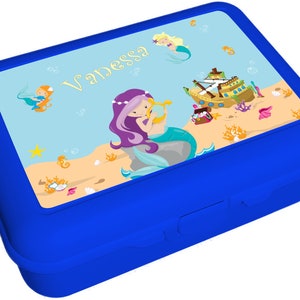 May include: Blue lunchbox with a mermaid theme. The lid features a mermaid with purple hair playing a harp, a ship, and the name "Vanessa".