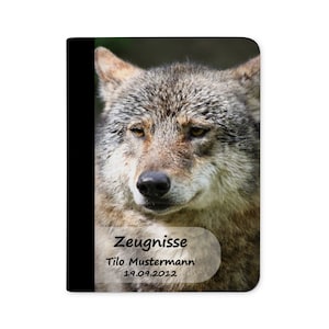 May include: A close-up of a wolf's face. The wolf has a grey and brown coat and is looking directly at the camera. The image is in focus and the wolf's eyes are sharp. The text "Zeugnisse" is visible in the lower right corner of the image. The text "Tilo Mustermann" and "19.09.2012" are also visible in the image.