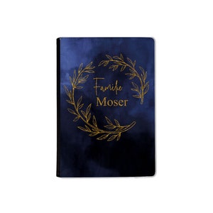 Könnte beinhalten: Ein dunkelblauer Notizbuchumschlag mit einem goldenen Kranzdesign und dem Text "Familie Moser".