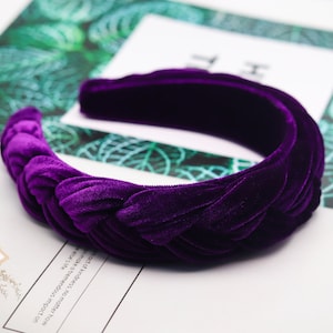 May include: A purple velvet headband with a knotted design. The headband is thick and wide, and it is perfect for adding a touch of elegance to any outfit.
