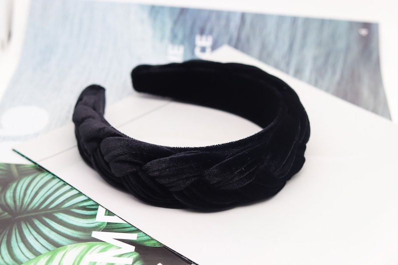 May include: A black velvet headband with a braided design. The headband is thick and wide, and it is perfect for adding a touch of elegance to any outfit.