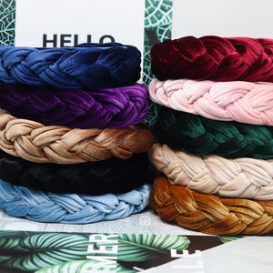 May include: A stack of ten braided velvet headbands in various colors, including navy blue, purple, beige, black, light blue, and brown.