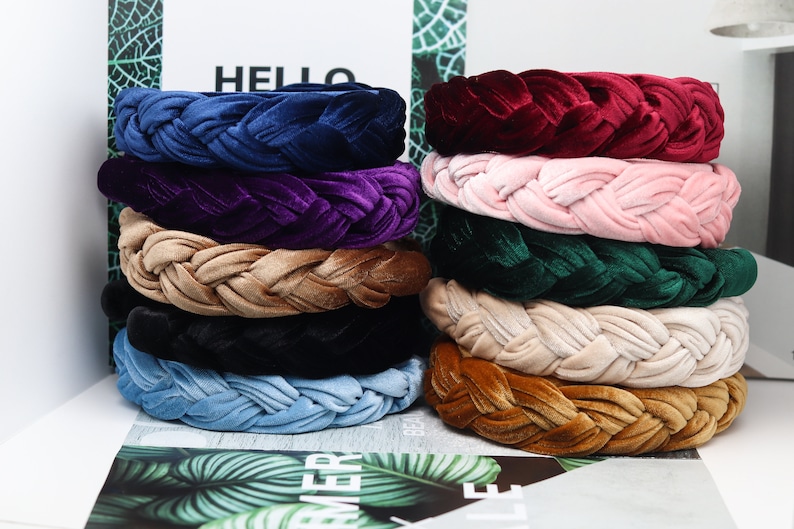 May include: A stack of ten braided velvet headbands in various colors, including navy blue, purple, beige, black, light blue, and brown.