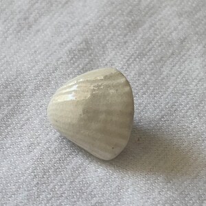 May include: A white ceramic cone-shaped object with a textured surface.