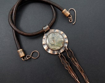 May include: A leather necklace with a copper pendant featuring a green and brown agate stone. The pendant has three copper teardrop-shaped charms hanging from it.