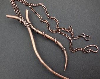 May include: A copper necklace with a unique pendant made of two twisted wire branches. The pendant is about 10 inches long and the chain is about 20 inches long.