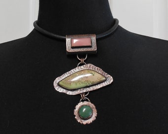 May include: A copper necklace with a green and white stone pendant and a smaller green stone pendant. The necklace is on a black leather cord.